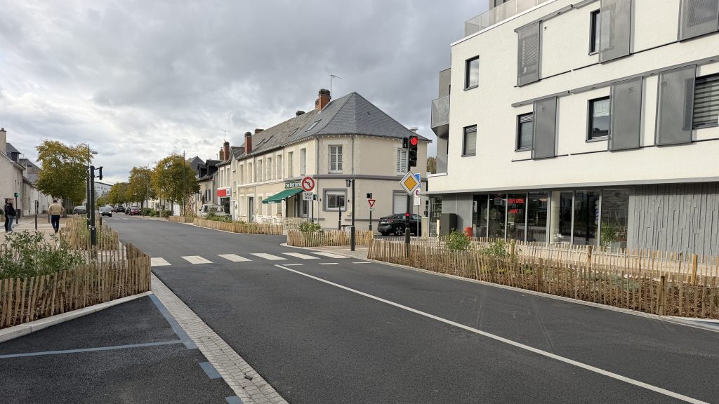 Rue urbaine moderne avec bâtiments blancs et clôtures en bois.